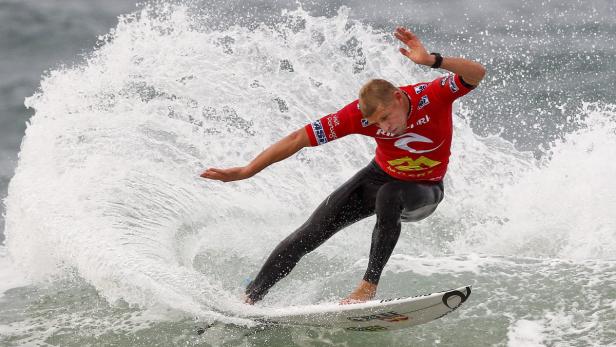 Ein Surfer in einem roten Trikot reitet auf einer Welle.