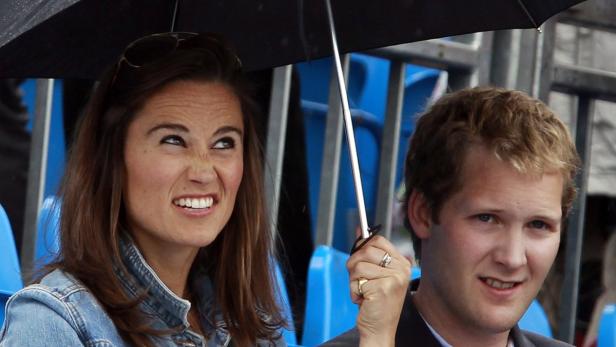 Pippa Middleton und ihr Begleiter sitzen unter einem Regenschirm.