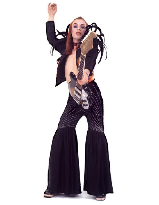 Eine Frau mit Gitarre in auffälliger Kleidung posiert vor einem weißen Hintergrund.