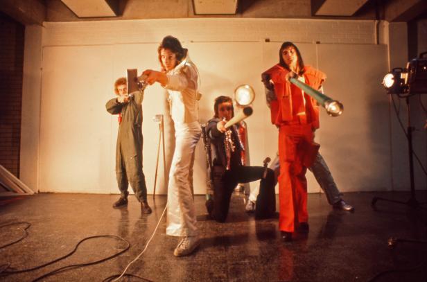 Eine Gruppe von Personen posiert mit Requisiten in einem Studio.