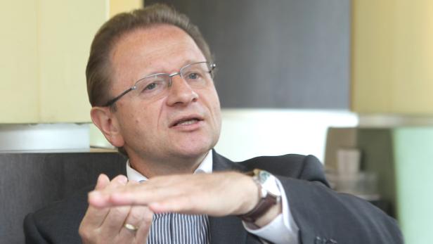 Ein Mann mit Brille und Anzug gestikuliert mit der Hand.
