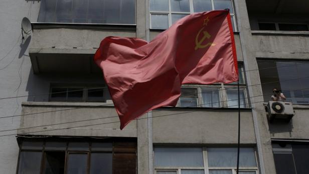 Eine rote Flagge der Sowjetunion weht vor einem grauen Gebäude.