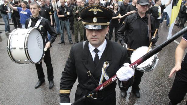 Eine Gruppe von uniformierten Männern mit Trommeln nimmt an einer Parade teil.