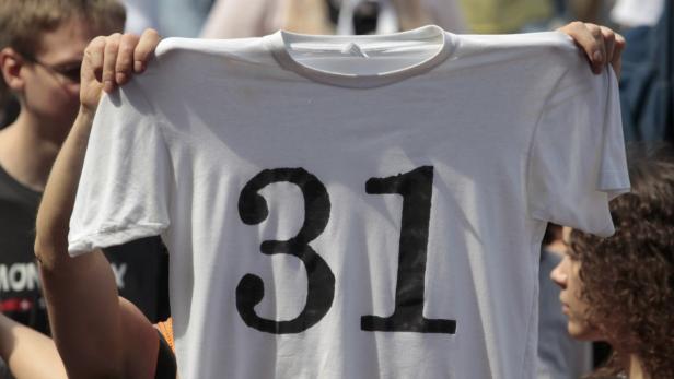 Eine Person hält ein weißes T-Shirt mit der schwarzen Zahl 31 hoch.