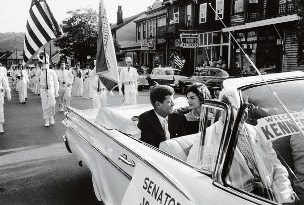 John F. Kennedy und Jackie Kennedy fahren in einer Parade in einem weißen Cabriolet.