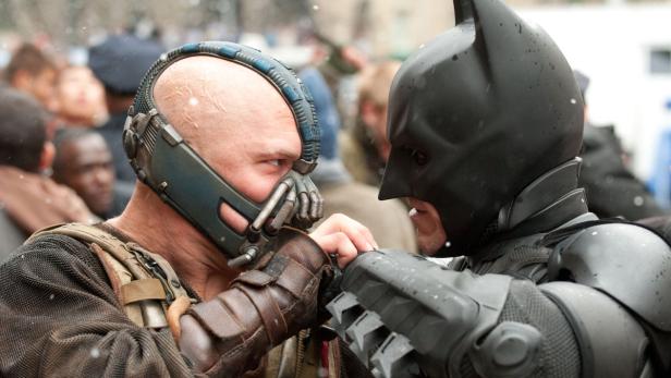 Bane und Batman stehen sich in einer Szene aus dem Film „The Dark Knight Rises“ gegenüber.