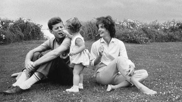 John F. Kennedy, Jackie Kennedy und ihre Tochter sitzen auf einer Wiese.