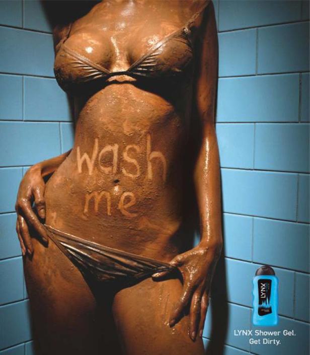 Eine Frau unter der Dusche, deren Körper mit Schlamm bedeckt ist, auf dem „Wash me“ steht.