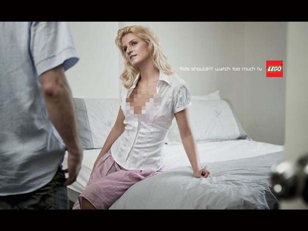 Eine Frau sitzt auf einem Bett, während ein Mann vor ihr steht; eine Lego-Werbung im Hintergrund.
