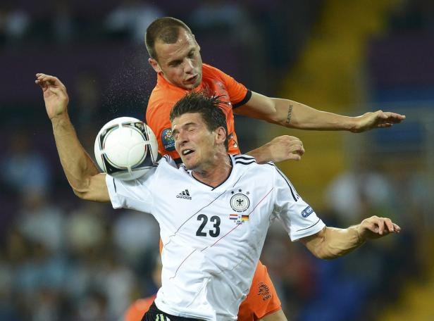 Ein deutscher und ein niederländischer Fußballspieler kämpfen um den Ball.