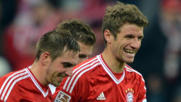 Thomas Müller lacht zusammen mit anderen Bayern-Spielern.