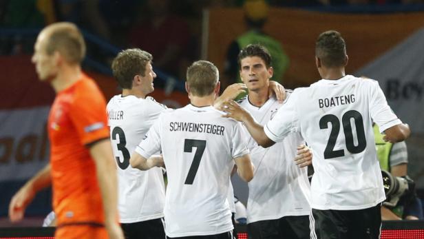 Deutsche Fußballspieler Müller, Schweinsteiger und Boateng umarmen einen Mitspieler.