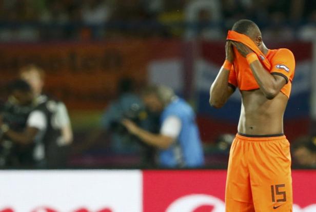 Ein niedergeschlagener Fußballspieler mit Trikot verdeckt sein Gesicht.