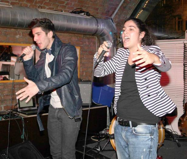 Zwei Personen singen in einem Club in Mikrofone.