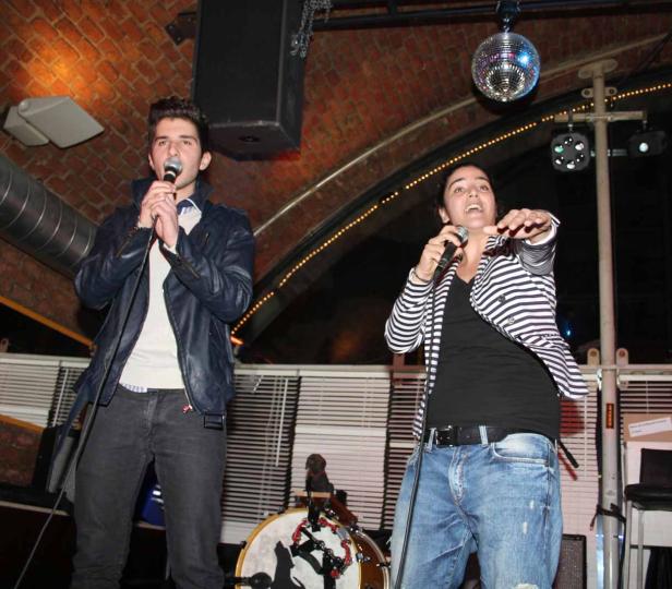 Ein Mann und eine Frau singen in einem Club mit einer Discokugel an der Decke.