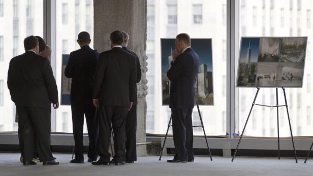 Eine Gruppe von Männern in Anzügen betrachtet Bilder des One World Trade Center.