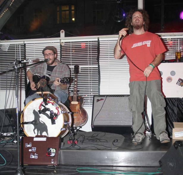 Zwei Musiker treten auf einer Bühne mit Gitarre, Schlagzeug und Gesang auf.