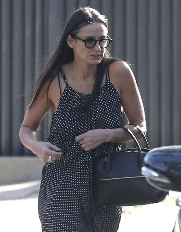 Demi Moore mit Brille und Handtasche in einem gepunkteten Jumpsuit.