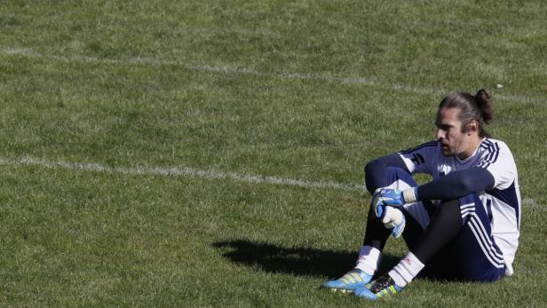 Ein Fußballtorwart sitzt auf dem Rasen.