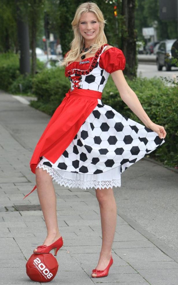 Eine Frau im Dirndl mit Fußballmuster posiert mit einem Fußball für die Europameisterschaft 2008.