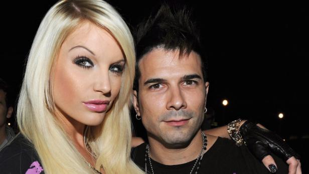 Ein Mann mit Irokesenschnitt posiert mit einer blonden Frau für ein Foto.