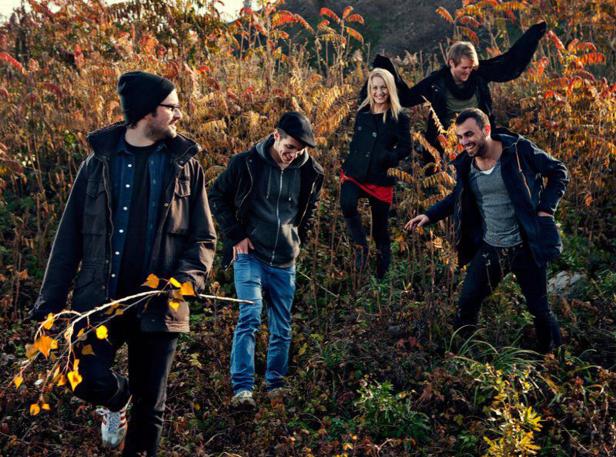 Fünf Freunde wandern im Herbst durch hohes Gras und Büsche.