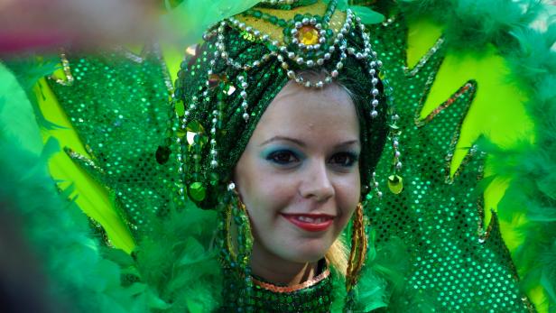 Eine Frau mit einem grünen Karnevalskostüm und Kopfschmuck lächelt.
