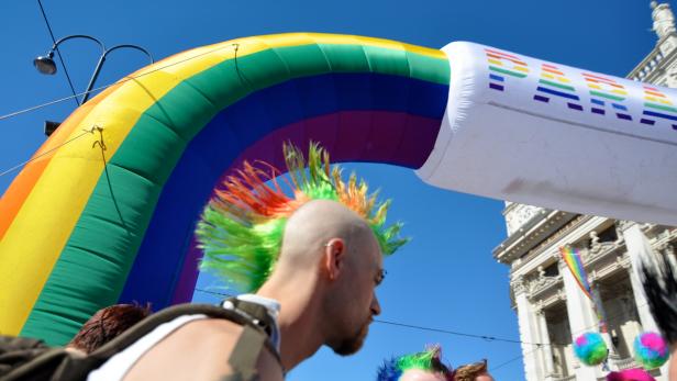 Ein Mann mit einem bunten Irokesenschnitt unter einem Regenbogenbogen mit der Aufschrift „Pride“.