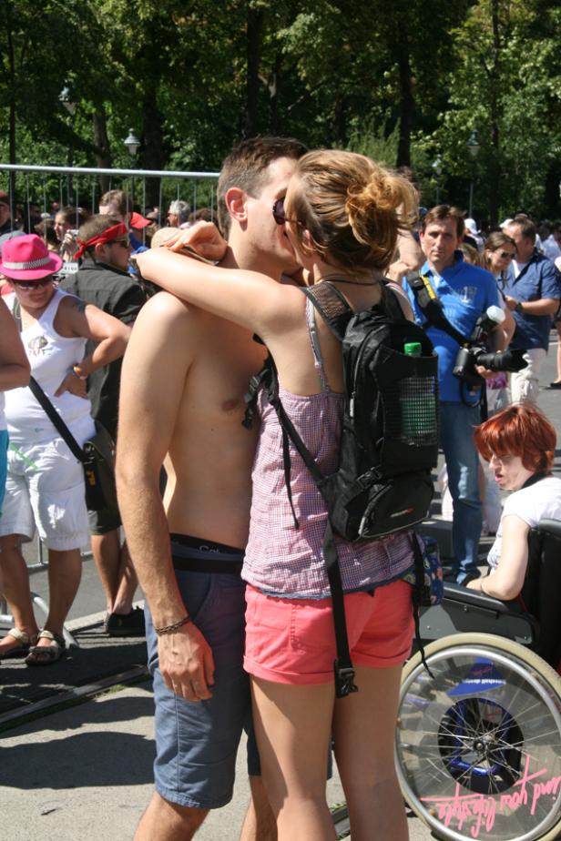 Ein Paar küsst sich inmitten einer Menschenmenge im Freien.