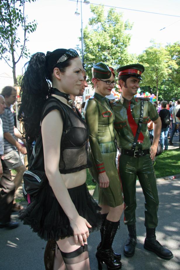 Drei Personen in auffälligen Outfits posieren auf einer Straße.