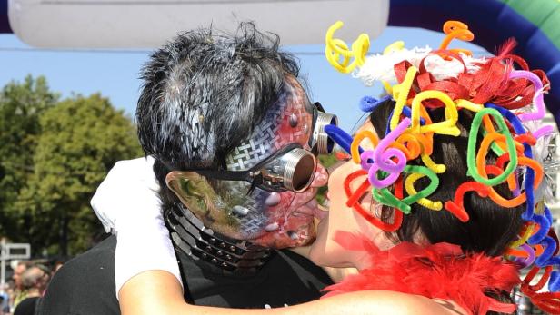 Ein Paar in Kostümen küsst sich; der Mann trägt Steampunk-Brille und Gesichtsbemalung, die Frau bunte Dekorationen im Haar.