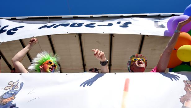 Menschen feiern auf einem Wagen mit bunten Kostümen und Luftballons.