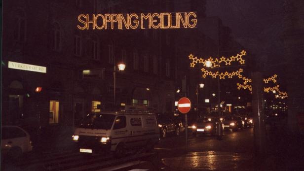 Eine abendliche Szene in Wien-Meidling mit Weihnachtsbeleuchtung und regem Straßenverkehr.