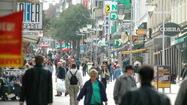 Eine belebte Einkaufsstraße mit vielen Menschen und Geschäften in einer Stadt.