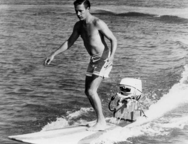 Ein Mann surft auf einem motorisierten Surfbrett auf dem Wasser.