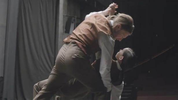 Zwei Personen in altmodischer Kleidung tanzen eng miteinander.