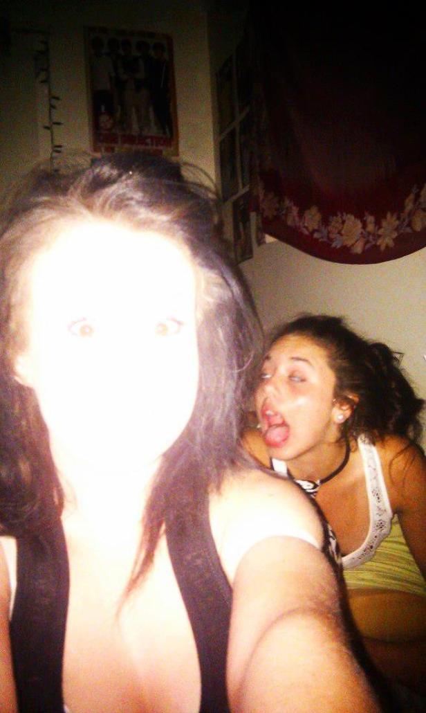 Zwei junge Frauen posieren in einem Raum, im Hintergrund ein Poster der Band One Direction.