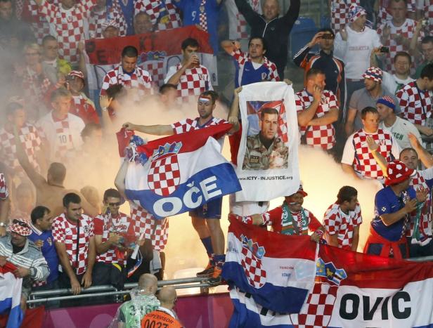 Kroatische Fußballfans zünden Rauchfackeln und schwenken Flaggen.