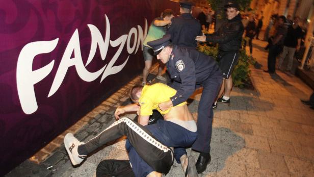 Polizisten greifen während einer Auseinandersetzung vor einem „Fanzone“-Banner ein.