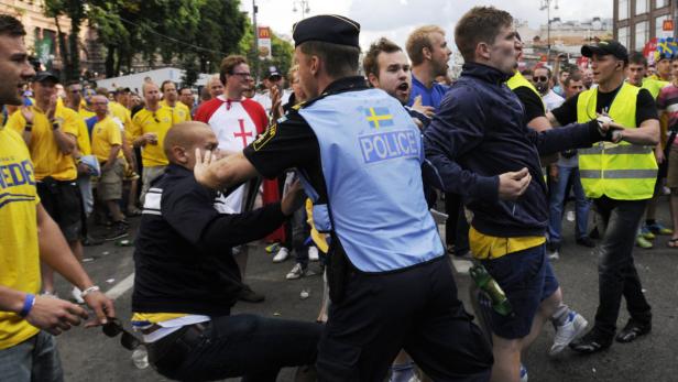 Ein schwedischer Polizist geht dazwischen, als sich Fußballfans streiten.