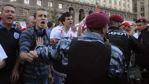 Polizisten stehen vor einer aufgebrachten Menschenmenge.