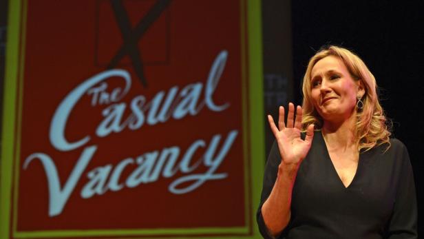 J.K. Rowling posiert vor einem Bildschirm mit dem Titel „The Casual Vacancy“.