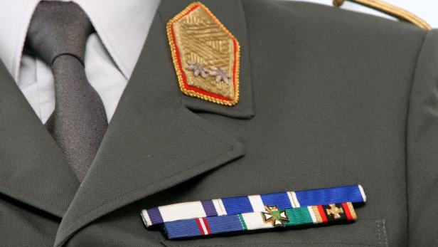 Nahaufnahme einer olivgrünen Militäruniform mit Auszeichnungen und Schulterklappen.