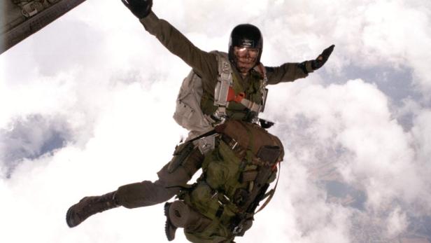 Ein Fallschirmspringer springt mit voller Ausrüstung aus einem Flugzeug.