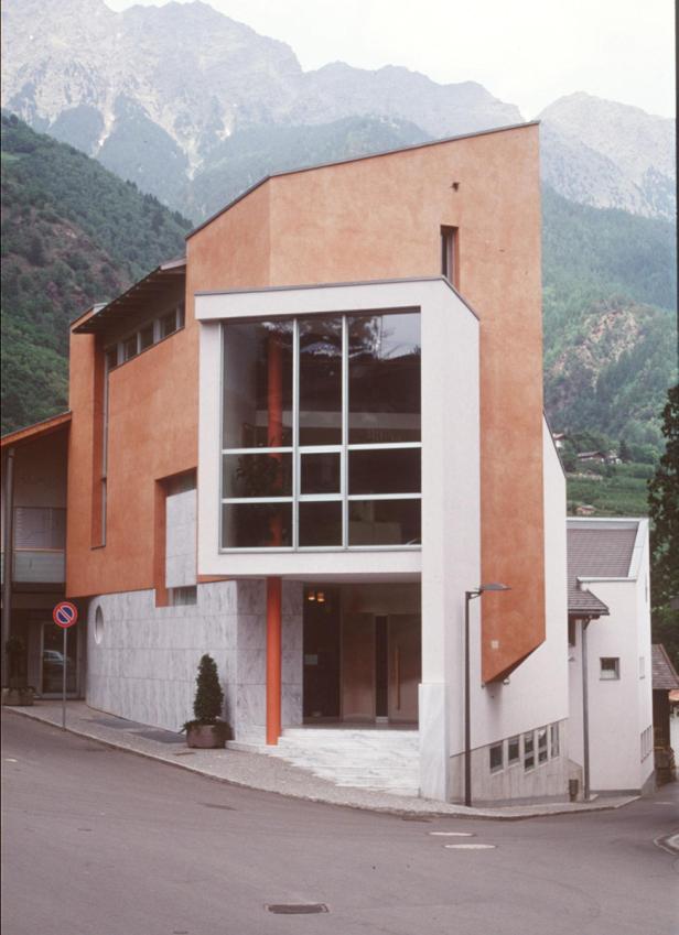 Ein modernes Gebäude mit großen Fenstern vor einer Bergkulisse.
