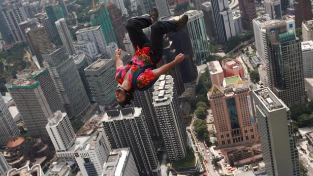 Ein Mann springt mit dem Fallschirm über eine Stadt mit vielen Hochhäusern.