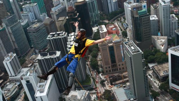 Ein Mann springt mit einem Fallschirm über eine Stadt mit vielen Wolkenkratzern.