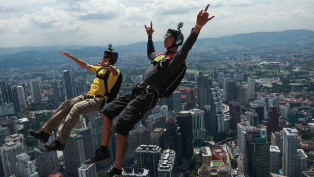Zwei Fallschirmspringer vor der Skyline einer Großstadt.