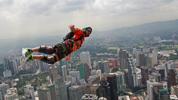 Ein Mann springt mit einem Fallschirm über eine Stadt mit vielen Wolkenkratzern.