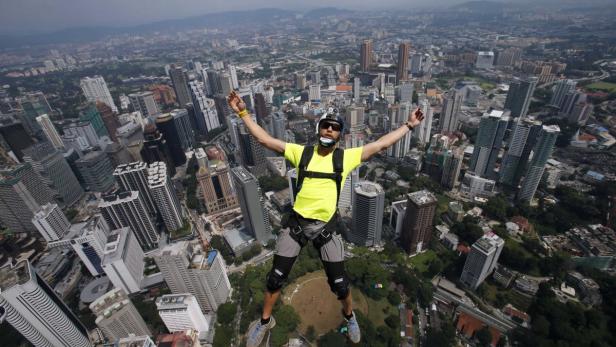 Ein Mann springt mit einem Fallschirm über eine Stadt mit vielen Wolkenkratzern.